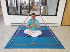 mr. Shah on a yoga mat under a metal triangle.