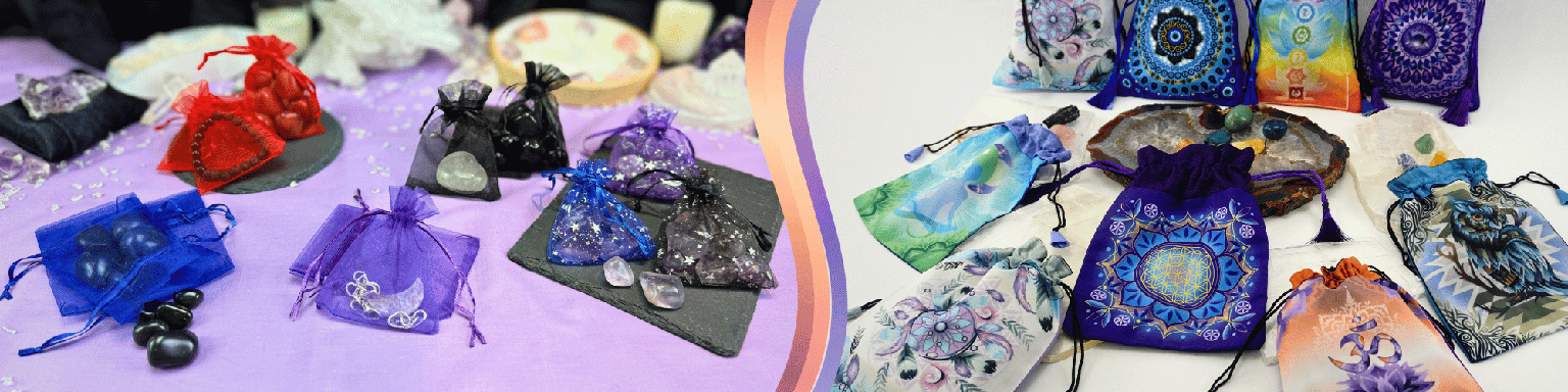 A display of colorful handmade drawstring pouches and small bags decorated with intricate patterns, gemstones, and spiritual designs, arranged on purple and white fabric.